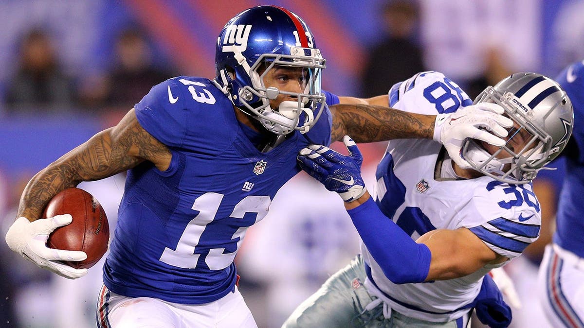 Odell Beckham Jr. stiff arms Dallas Cowboys safety Jeff Heath during an NFL game.