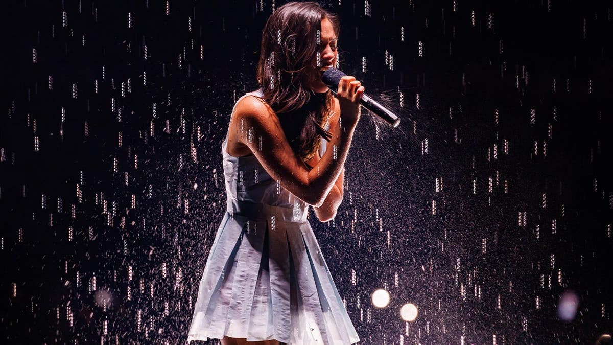 Olivia Rodrigo singing on stage in blue dress
