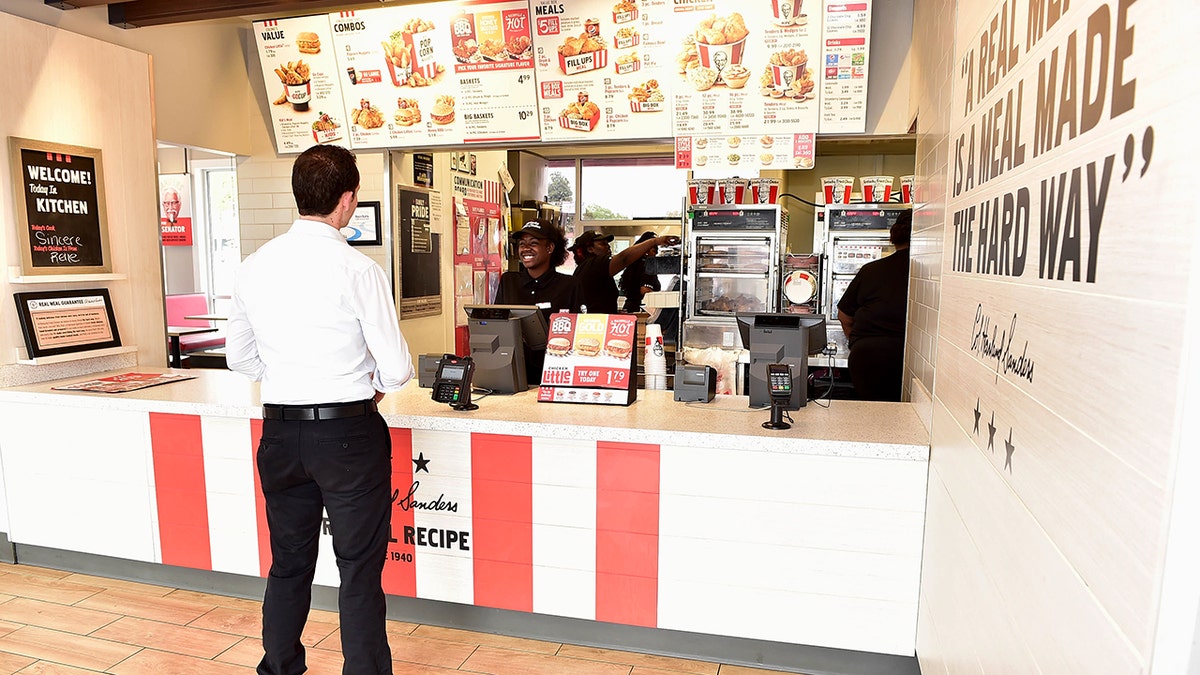 A man orders from the register at a KFC restaurant.