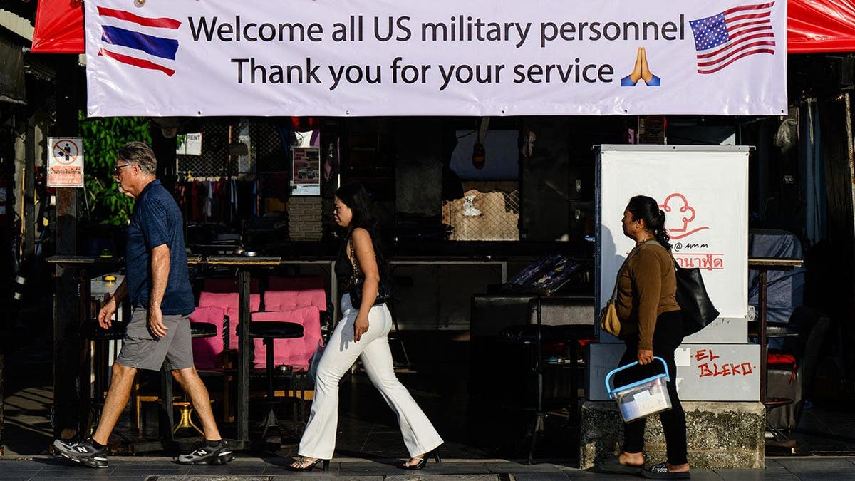 Pedestrians walk past a banner welcoming U.S. military personnel outside a bar in Pattaya.