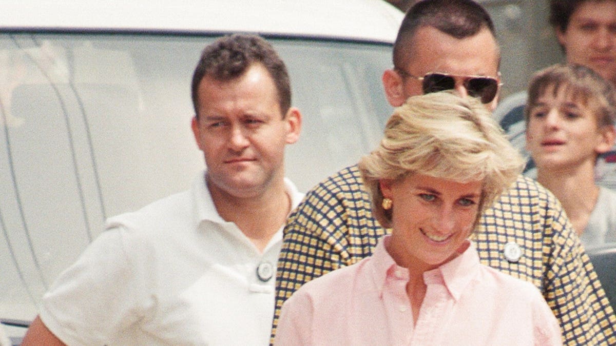 Paul Burrell, butler to Princess Diana, stands in the background in a white shirt during a Bosnia-Herzegovina visit.
