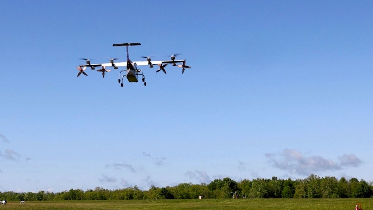 A pilotless cargo plane flies above a field.