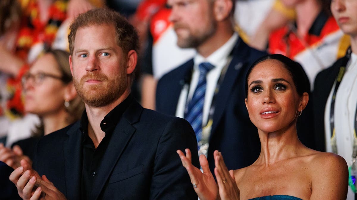 Prince Harry and Meghan stand together clapping during the Invictus Games closing ceremony.