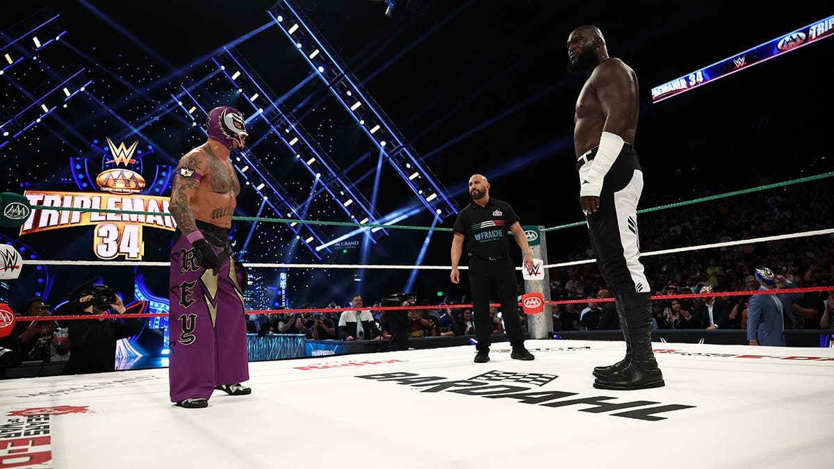 Rey Mysterio and Omos face off during a wrestling match.