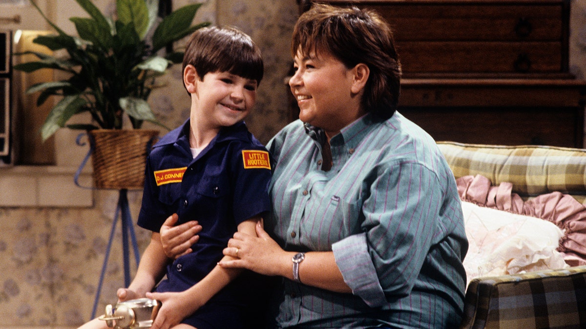 Roseanne Barr sits next to Michael Fishman on a television set.