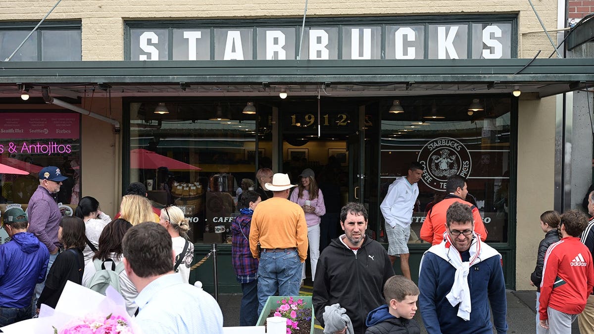 People queue outside the first Starbucks coffee shop opened in 1971 in Seattle.