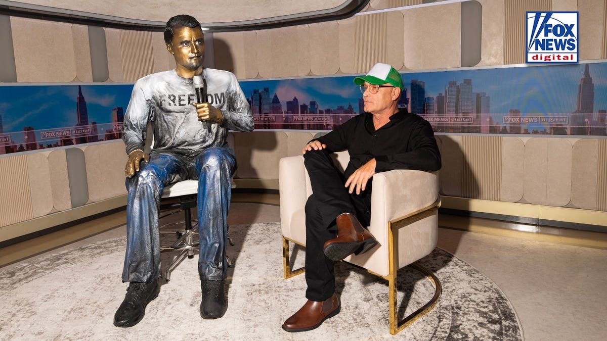 Artist Sergio Furnari sits beside his sculpture of Charlie Kirk in Times Square.
