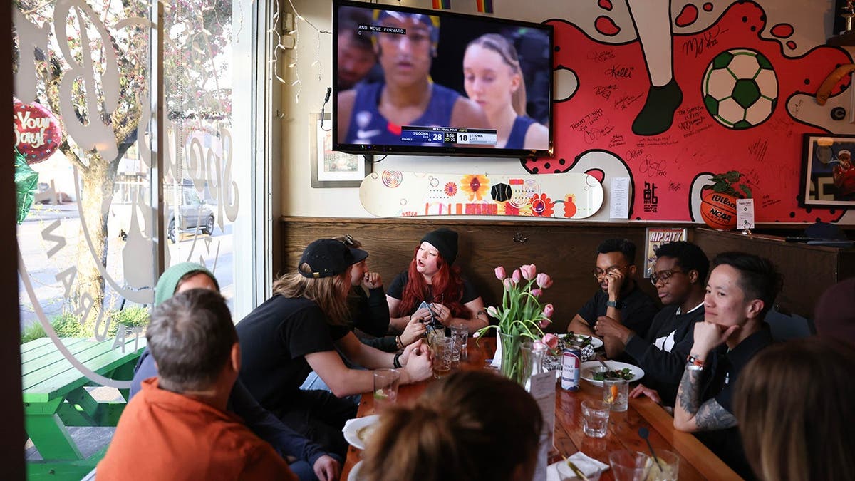 Patrons watch the NCAA Women's Basketball Championship semifinal game on a TV at The Sports Bra in Portland, Oregon.