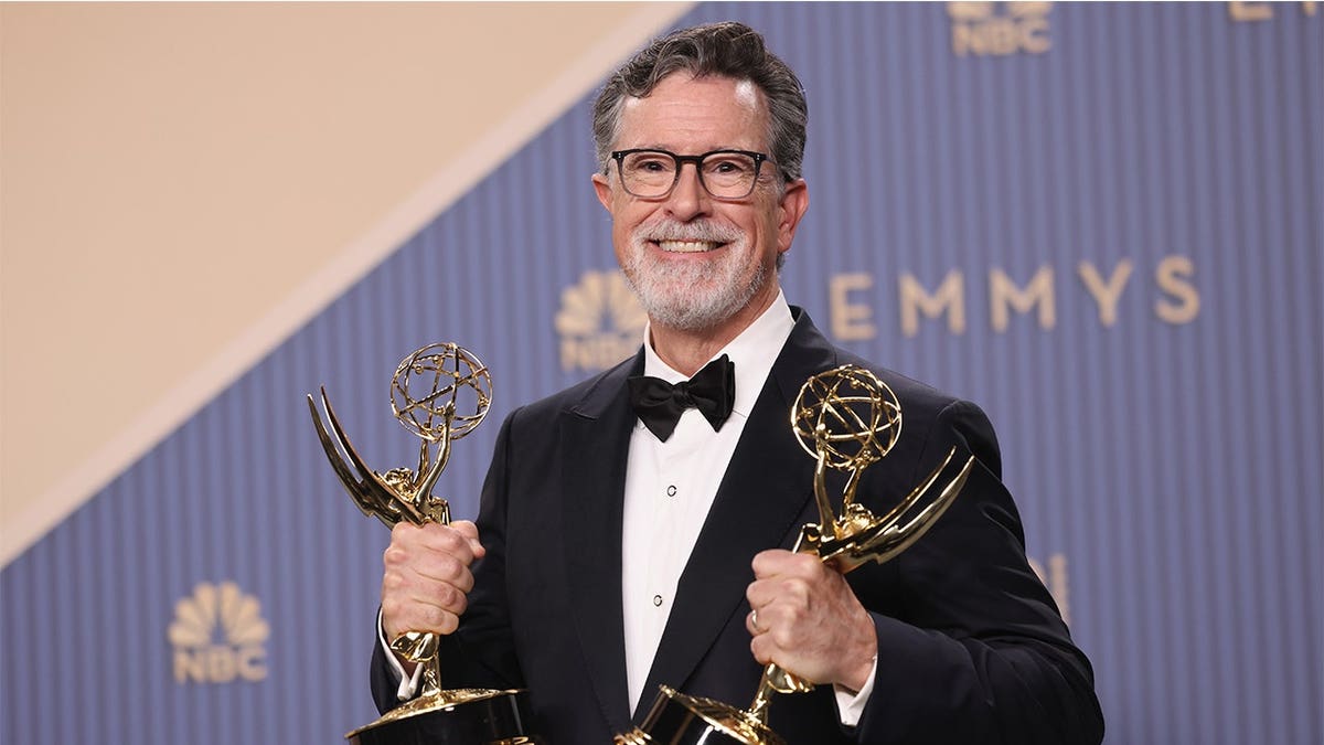 Stephen Colbert poses backstage holding an Emmy Award at the Peacock Theater.