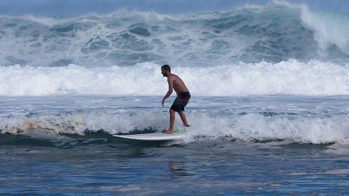 Surfer rides a wave at Saint-Gilles les bains beach in La Réunion.