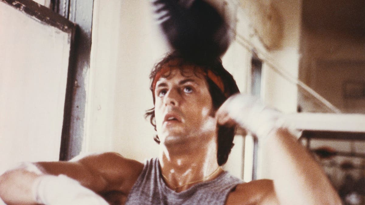 Sylvester Stallone as Rocky Balboa trains with a punchbag.