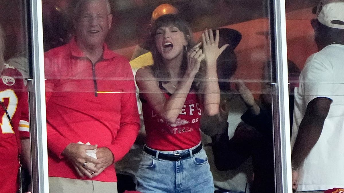 Taylor Swift celebrates with her father Scott Swift in the stands during an NFL game.