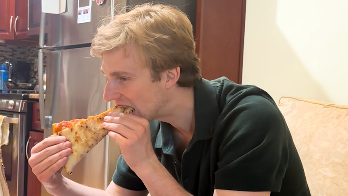 Tim Donohue eats a slice of pizza.