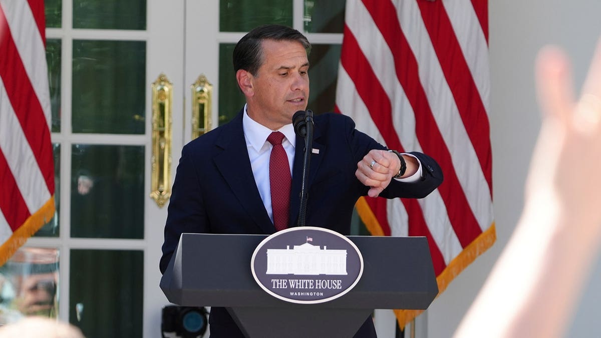 Attorney General Todd Blanche checks his watch while speaking at a news briefing in the Rose Garden.