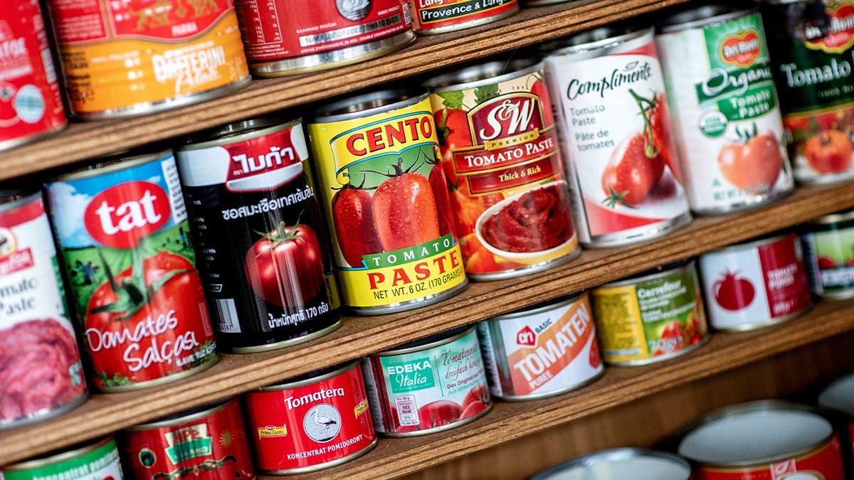 Tomato paste cans from different countries stand on a shelf in a dining room.