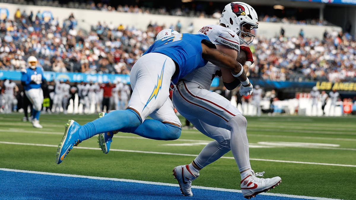 Trey McBride catches a touchdown pass against Derwin James Sr. during an NFL game.