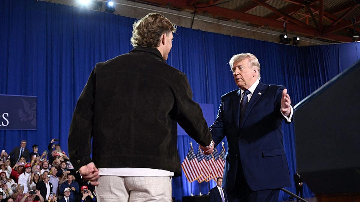 President Donald Trump is welcomed by quarterback Jaxson Dart indoors.