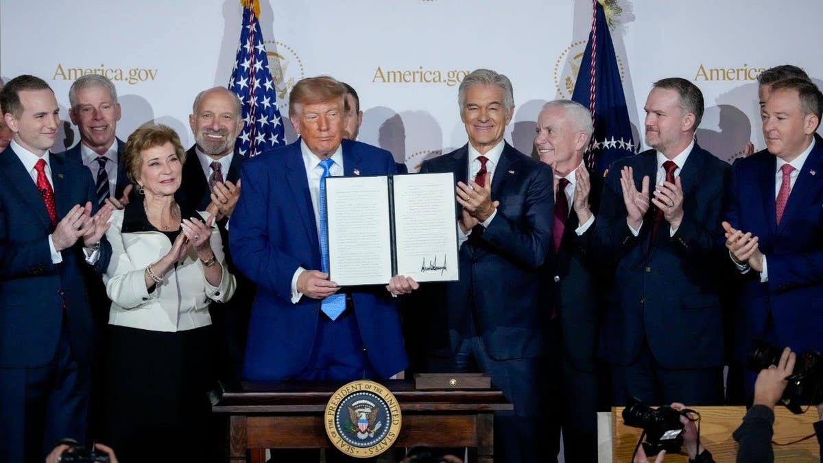 President Donald Trump displays a signed executive order during the launch of America.gov