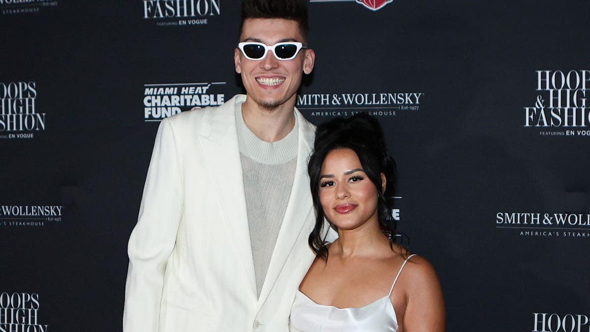 Tyler Herro and Katya Elise Henry pose on a red carpet.