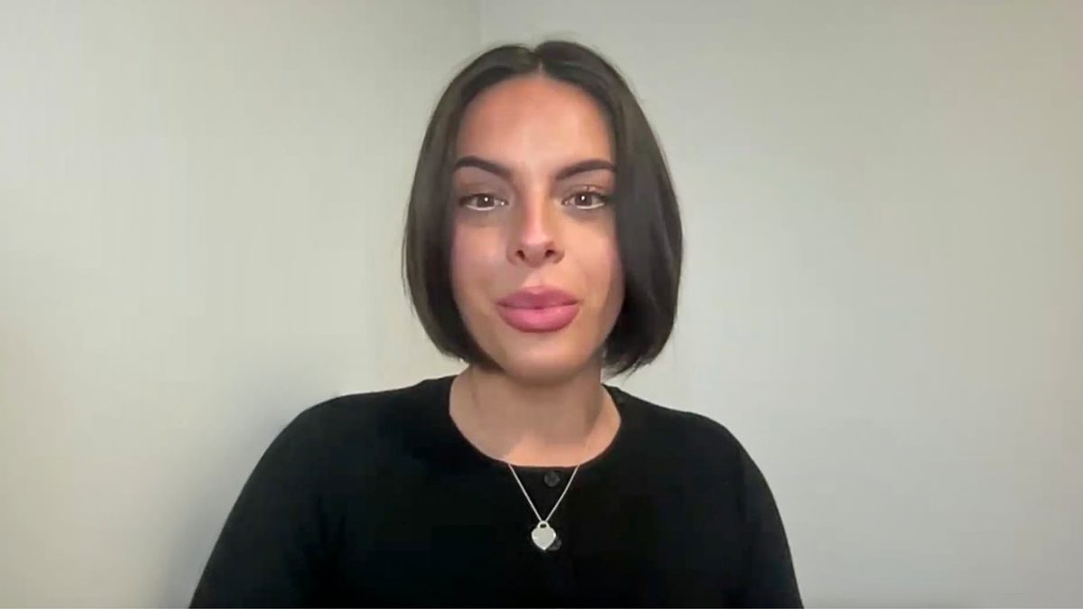 woman with short dark hair and brown eyes in a black sweater looks at camera during interview