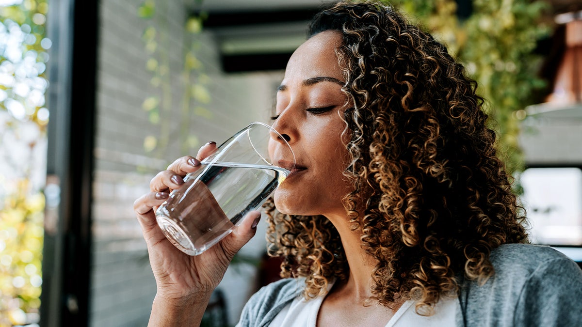 A woman drinks a glass of water.
