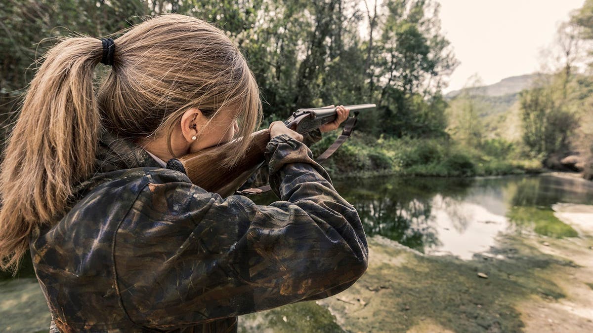 Woman bird hunter stands outdoors.