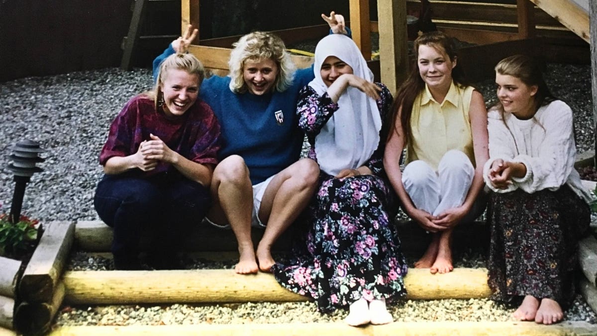 teenage girls sit on stoop outdoors laughing