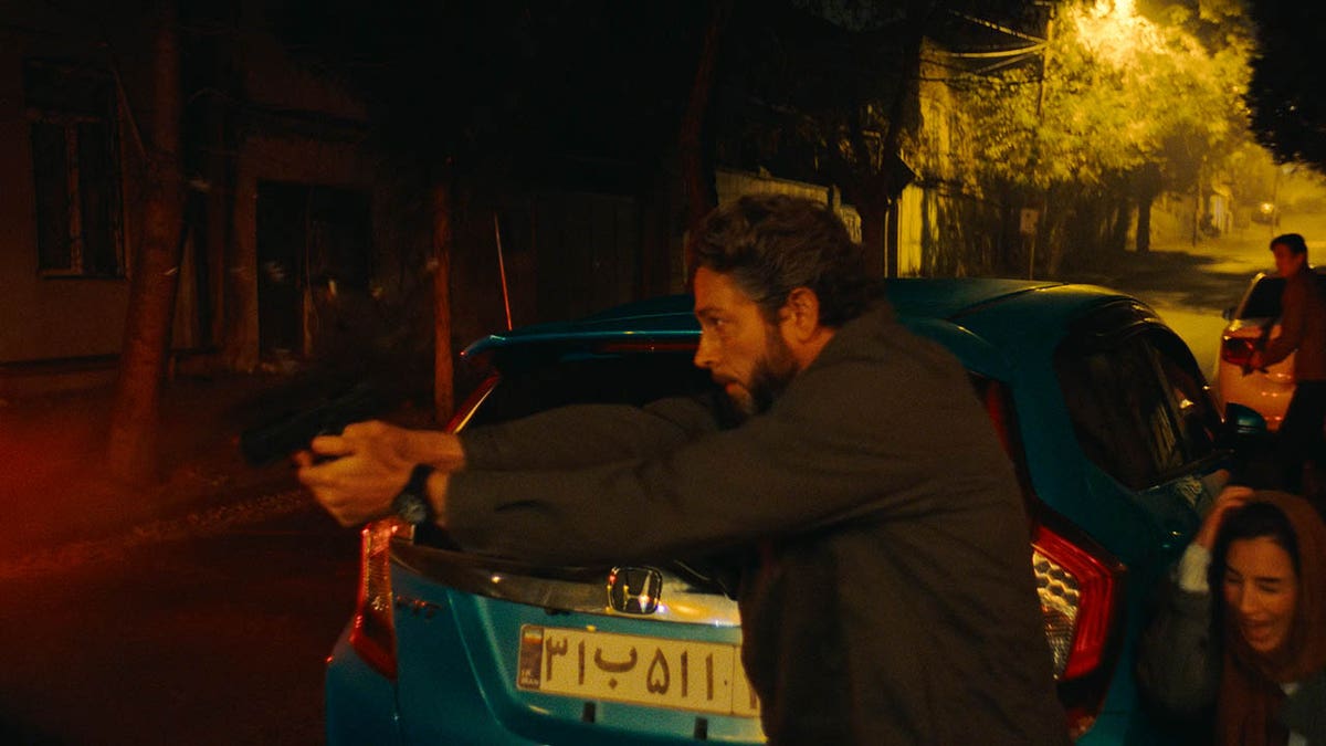 Zachary Levi holds a gun in The Fix