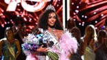 Justus Kelley after winning the crown for Miss USA wearing a pink frilly gown and holding a bouquet of flowers.