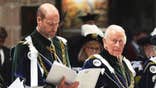 Prince William and King Charles in royal robes looking stern inside a church.