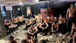 Partially clothed young men sit and stand inside the basement of an Alpha Epsilon Pi fraternity house in Madison, Wisconsin.