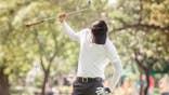 An angry golfer attempts to break his golf club.