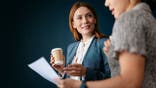 Two business women collaborate on a project in an office setting.