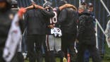 Caleb Williams is helped off the field at Soldier Field.
