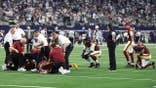 Jayden Daniels #5 lies on the field as medical staff attend to him during a game.