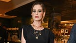 Kelly Osbourne poses in black dress.