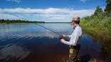 A man fishes on a river with a spinning rod.
