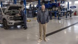Nate Bargatze with his hands in his pockets inside the Ford factory.