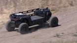 An Overland AI autonomous ground vehicle drives across rugged, dusty terrain during a demonstration in Washington state.