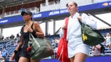 Su-Wei Hsieh and Jelena Ostapenko walk onto the court before a women's doubles match.