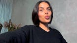 Woman with short dark hair and dark eyes makes kissy face at camera in selfie