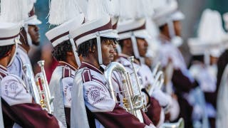 Un tubista de una banda de música le da una paliza a un hombre en un partido de fútbol americano universitario sin perder el ritmo ni un segundo