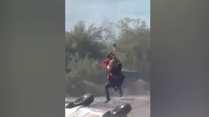 A stranded driver is hoisted from his overturned truck by authorities