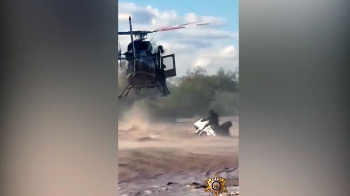 A Maricopa County Sheriff’s Office helicopter crew responds to rescue a man stranded on an overturned truck in Arizona floodwaters.