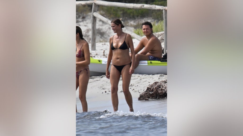 Yasmin Le Bon walking along the beach in Italy.