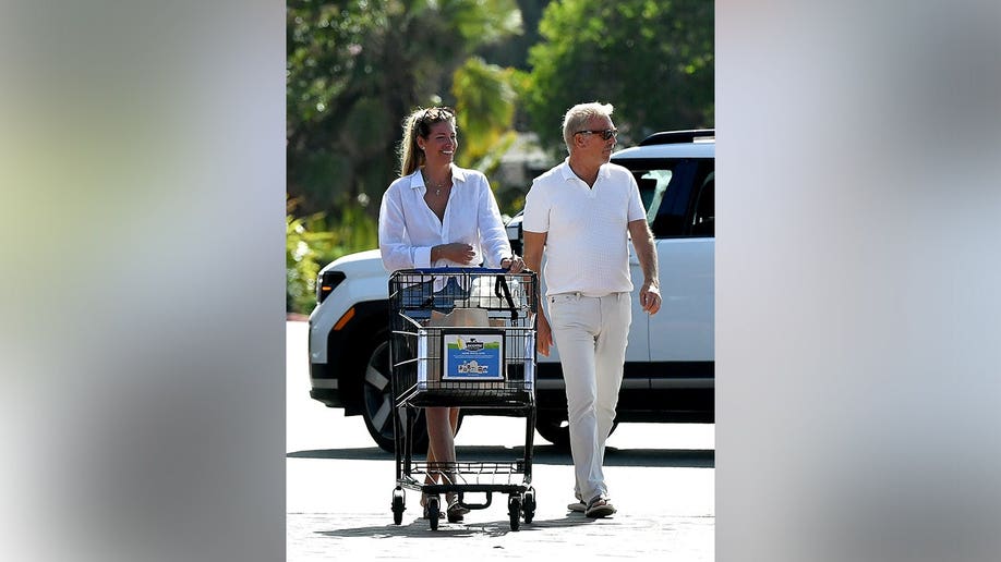 Kevin Costner and the lifestyle coach laughing in the parking lot.
