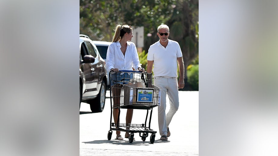 Kevin Costner and Jennifer Milburn matched in white outfits and black sunglasses.