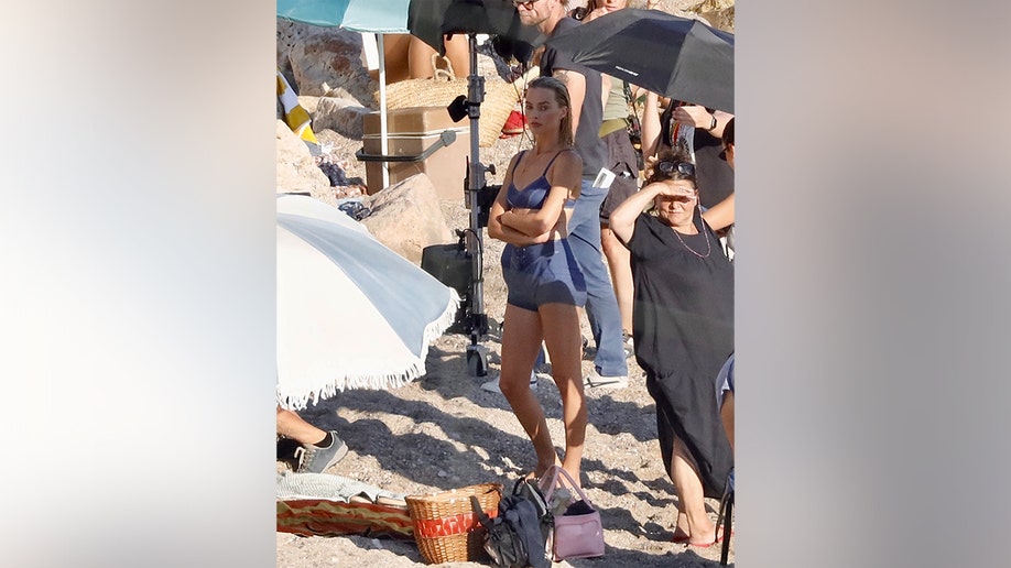 Margot Robbie standing in the shade as she waited to film her scene.