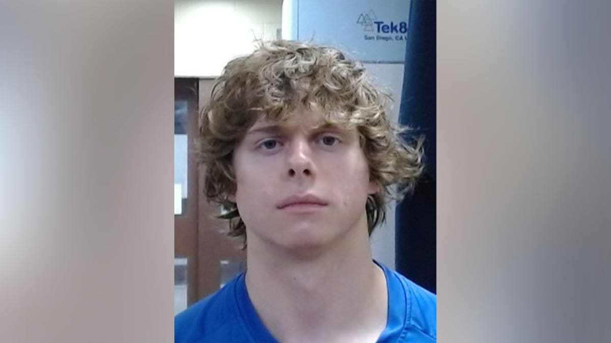 Aaron Christian, 18, appears in a booking photo wearing a blue shirt, with curly blond hair and a neutral expression.