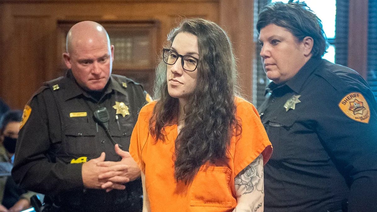 Bailey Boswell, escoltado por la policía en el juzgado, vestido con un mono naranja.